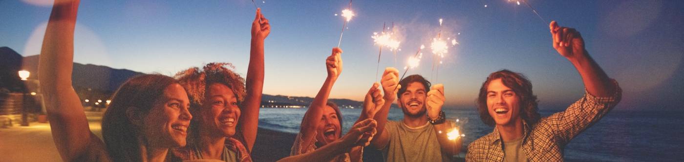 Friends holding sparklers on the beach