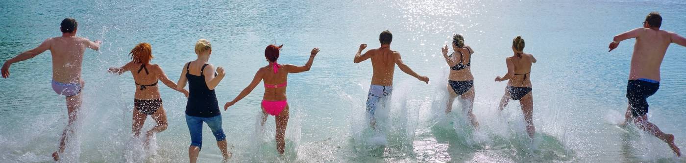 A group of friends running to the water on the beach